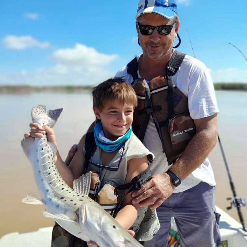 Padre e hijo sosteniendo un gran surubí durante excursión de pesca en Villa Urquiza.