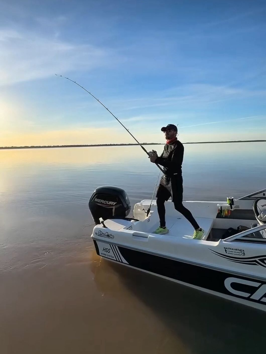 Pescador lanzando la caña desde una embarcación moderna en el río Paraná, salida de pesca con Punto Relax