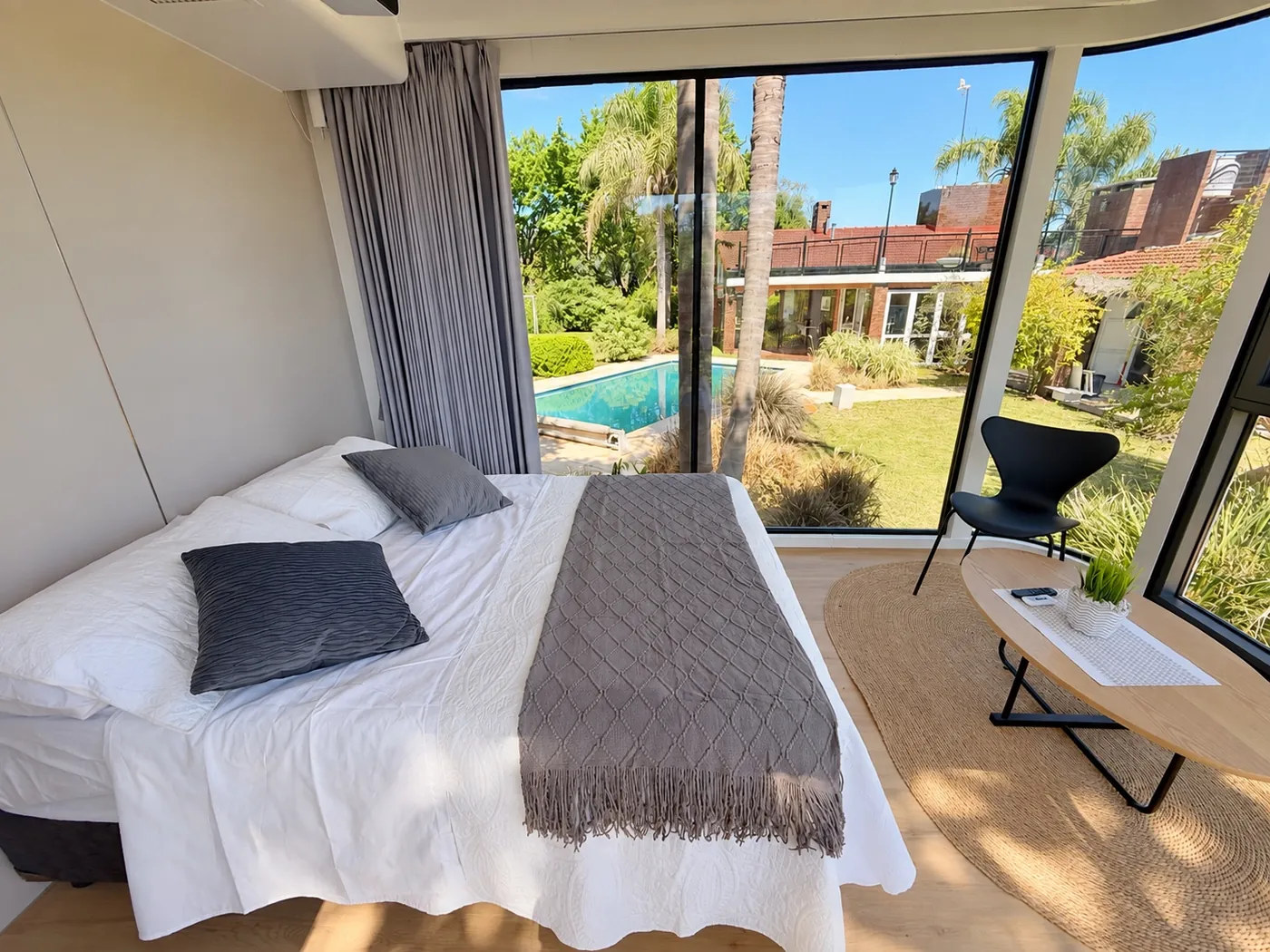 Interior de Cápsula Premium RDO con cama matrimonial, ventanales panorámicos y vista a la piscina privada en Entre Ríos