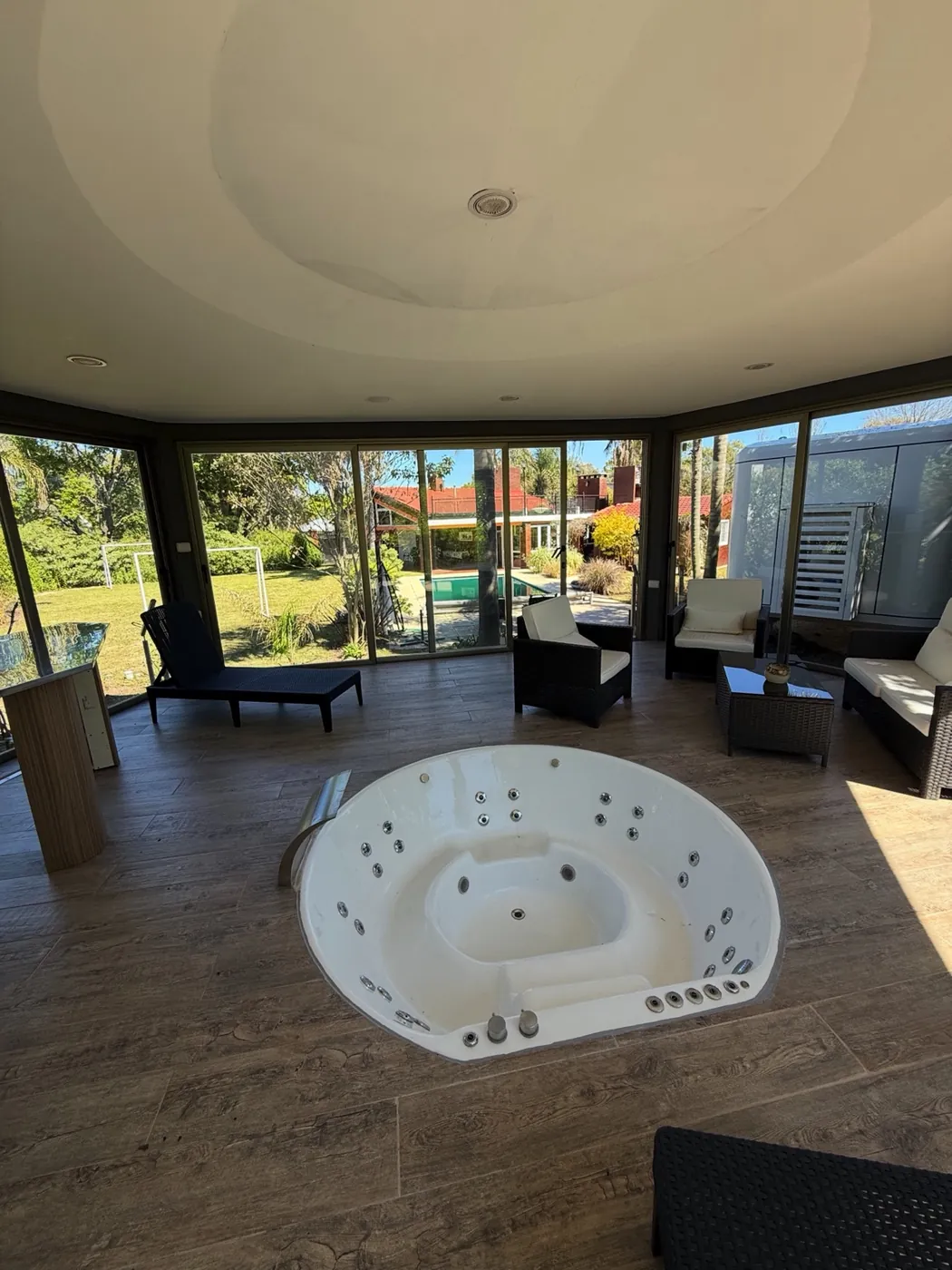 Sector de hidromasaje con grandes ventanales y vista al jardín y piscina en alojamiento premium de Entre Ríos